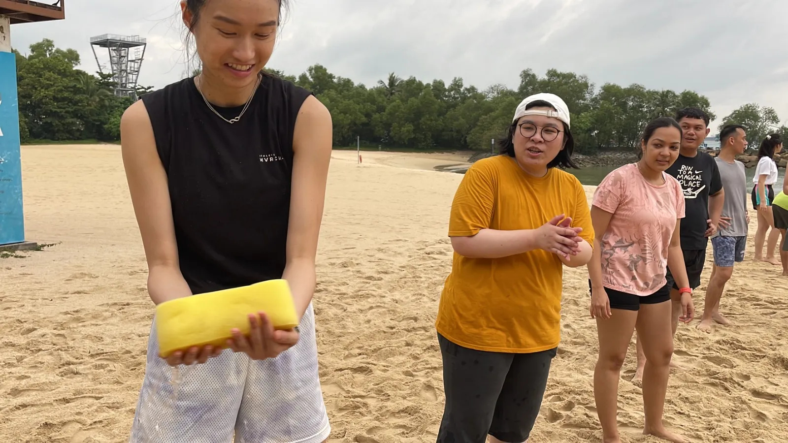 Young adults on a sandy beach participating in a water activity, smiling and interacting.
